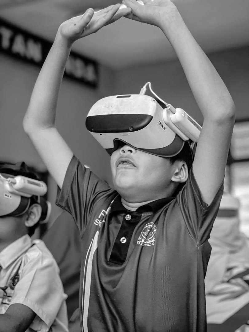 A student reaching up with a VR headset on, in black and white